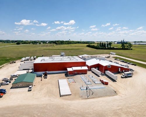 Upper Iowa Beef starting to grow, expansions made. Red siding, blue sky, white clouds, green grass.