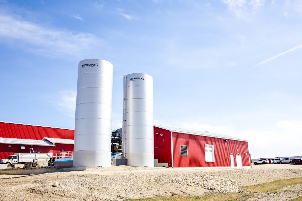 Waste Water area in front of plant, double silo and red building with blue sky.