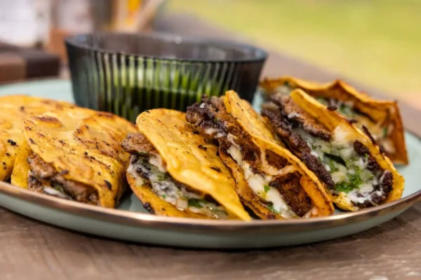 Smashed Tacos, wooden table outdoors, green dish, tacos on plate.