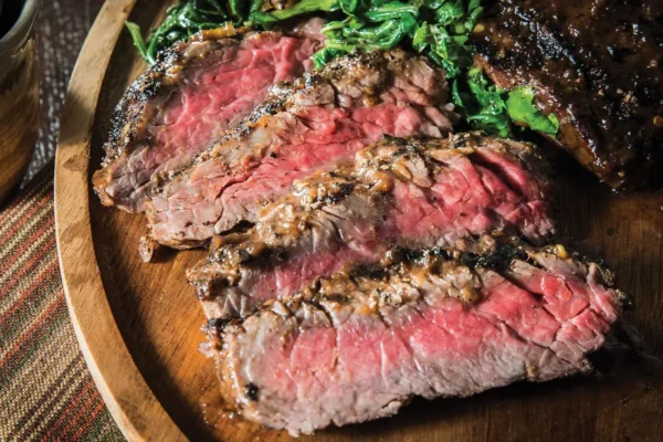Jerk Spiced Sirloin Flap Steak, medium cooked sirloin flap steak with lettuce garnish on wooden serving trey.