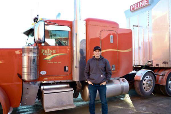 Peine Farms, red semi trick, detailed, Carhart grey sweatshirt, black cap.