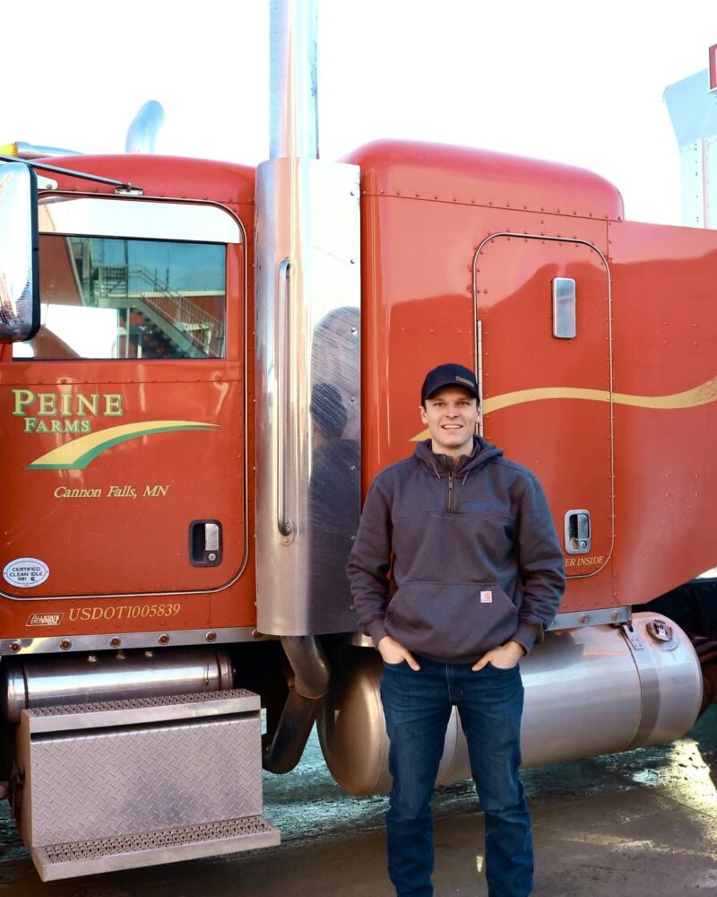 Peine Farms, red semi trick, detailed, Carhart grey sweatshirt, black cap.