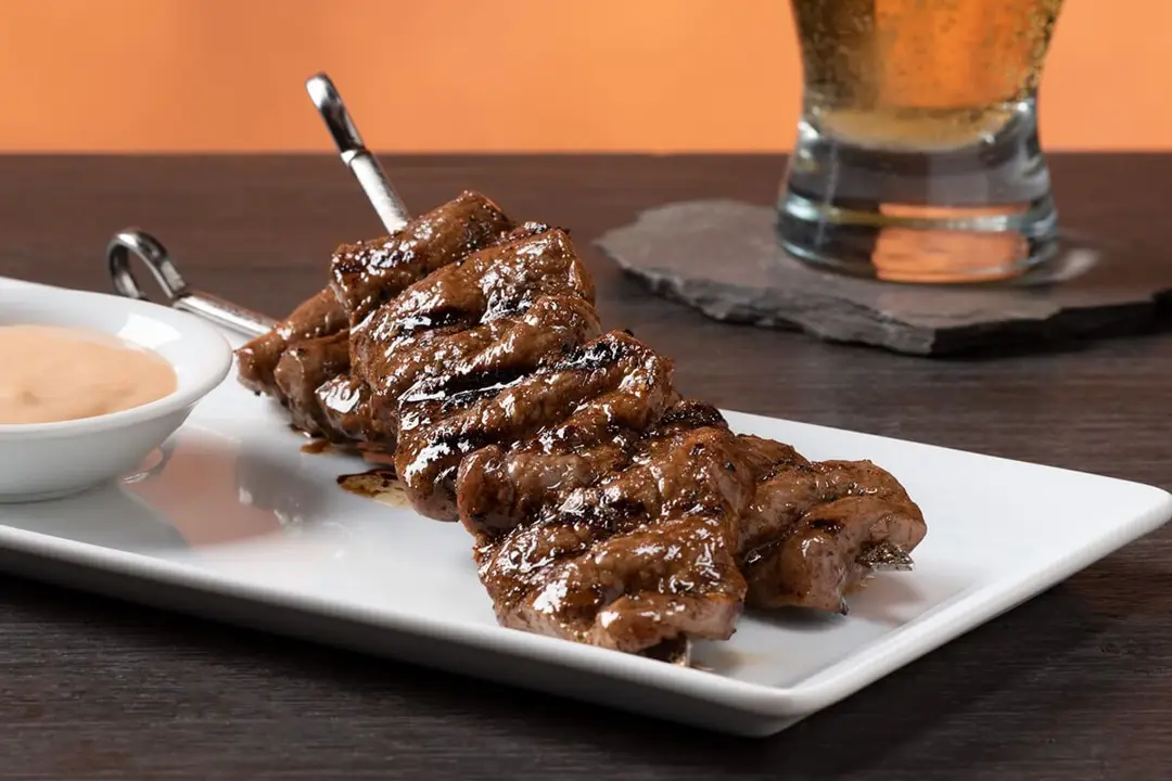 Quick Sirloin Skewers with Chipotle Dipping Sauce, white serving plate and metal skewers on wooden table.